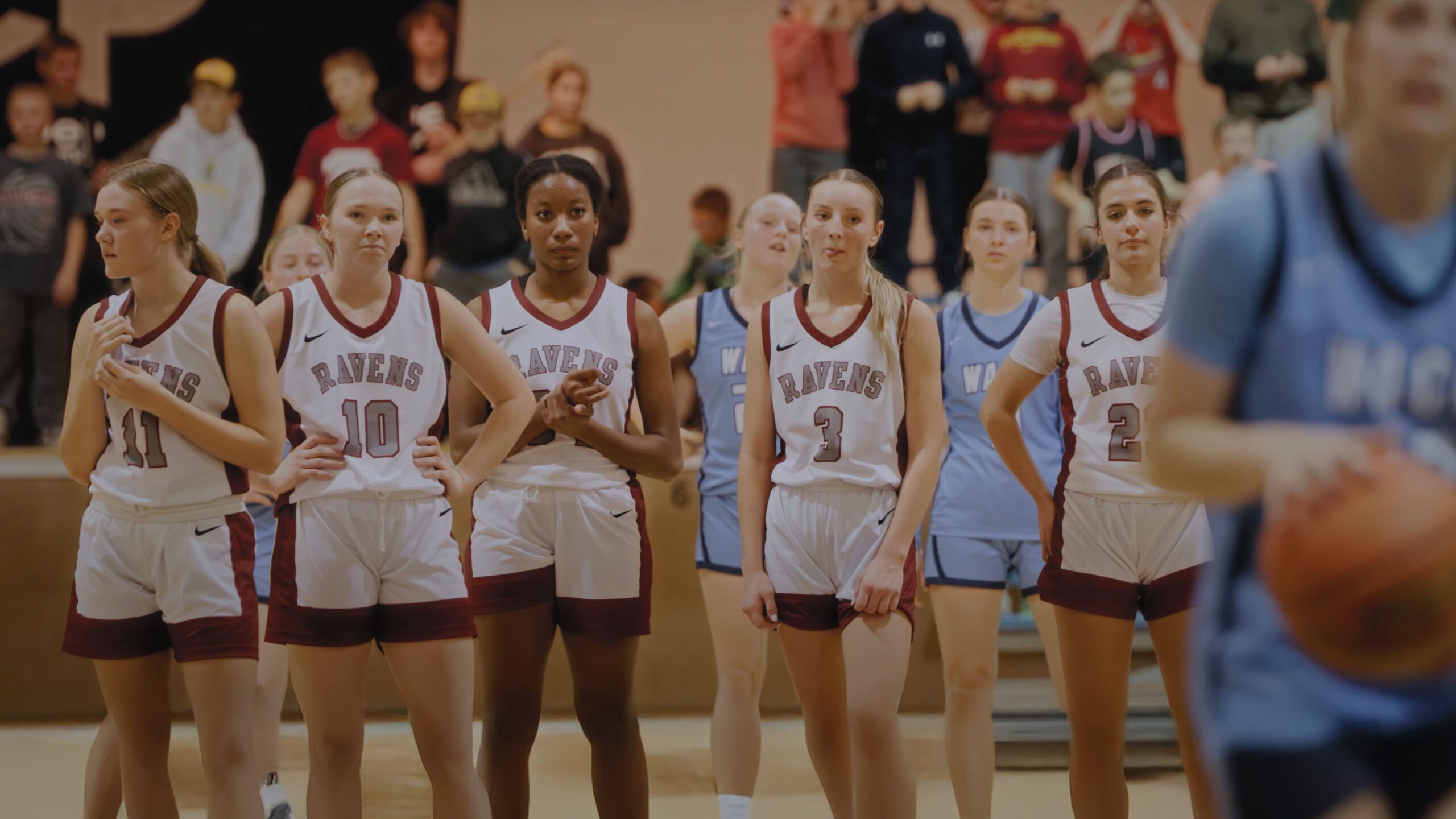 varsity girls players watching away team shoot free throws with a storytelling shot.